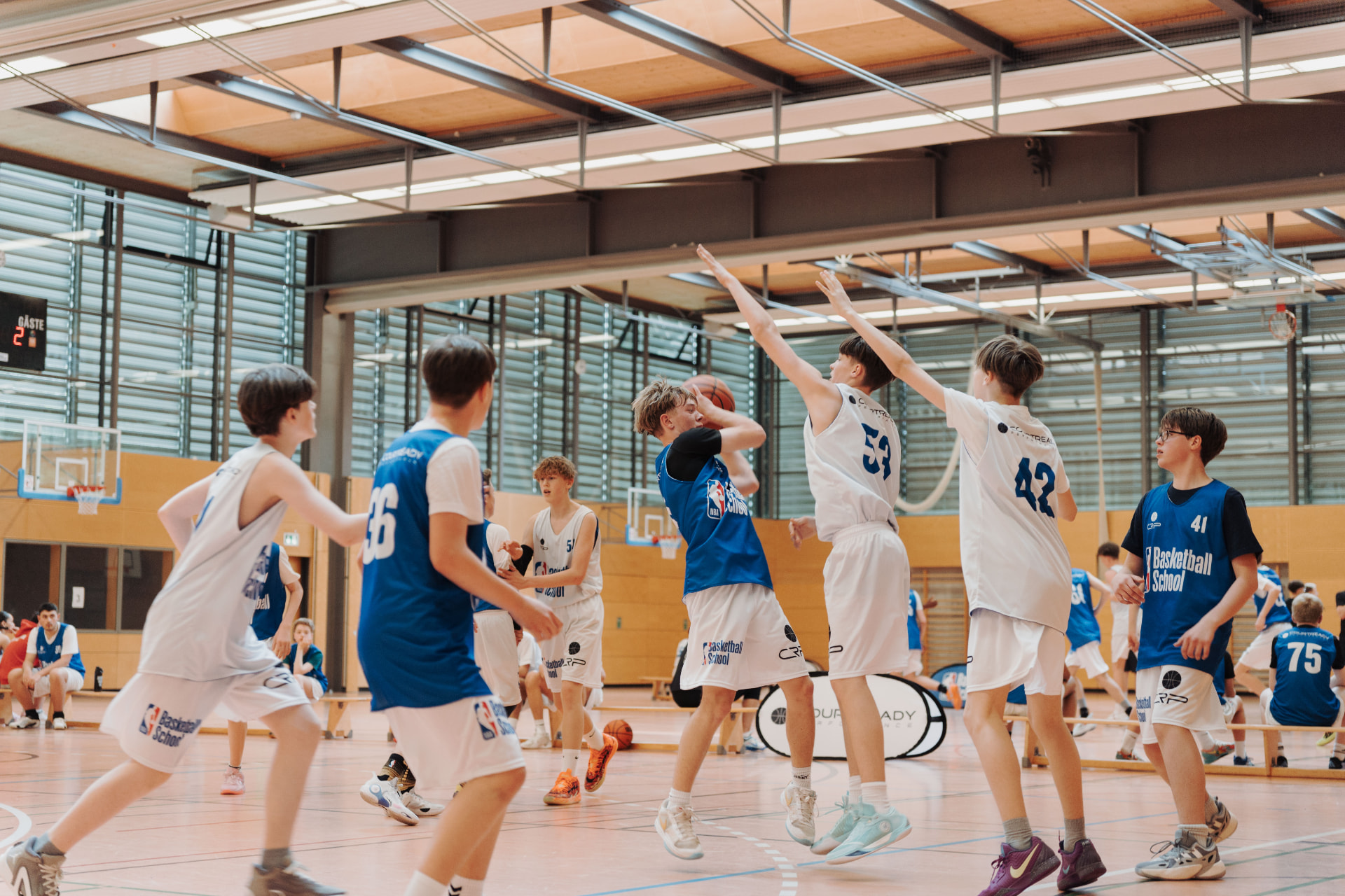 Jugendlicher Spieler zieht beim NBA Basketball School Camp zum Korb